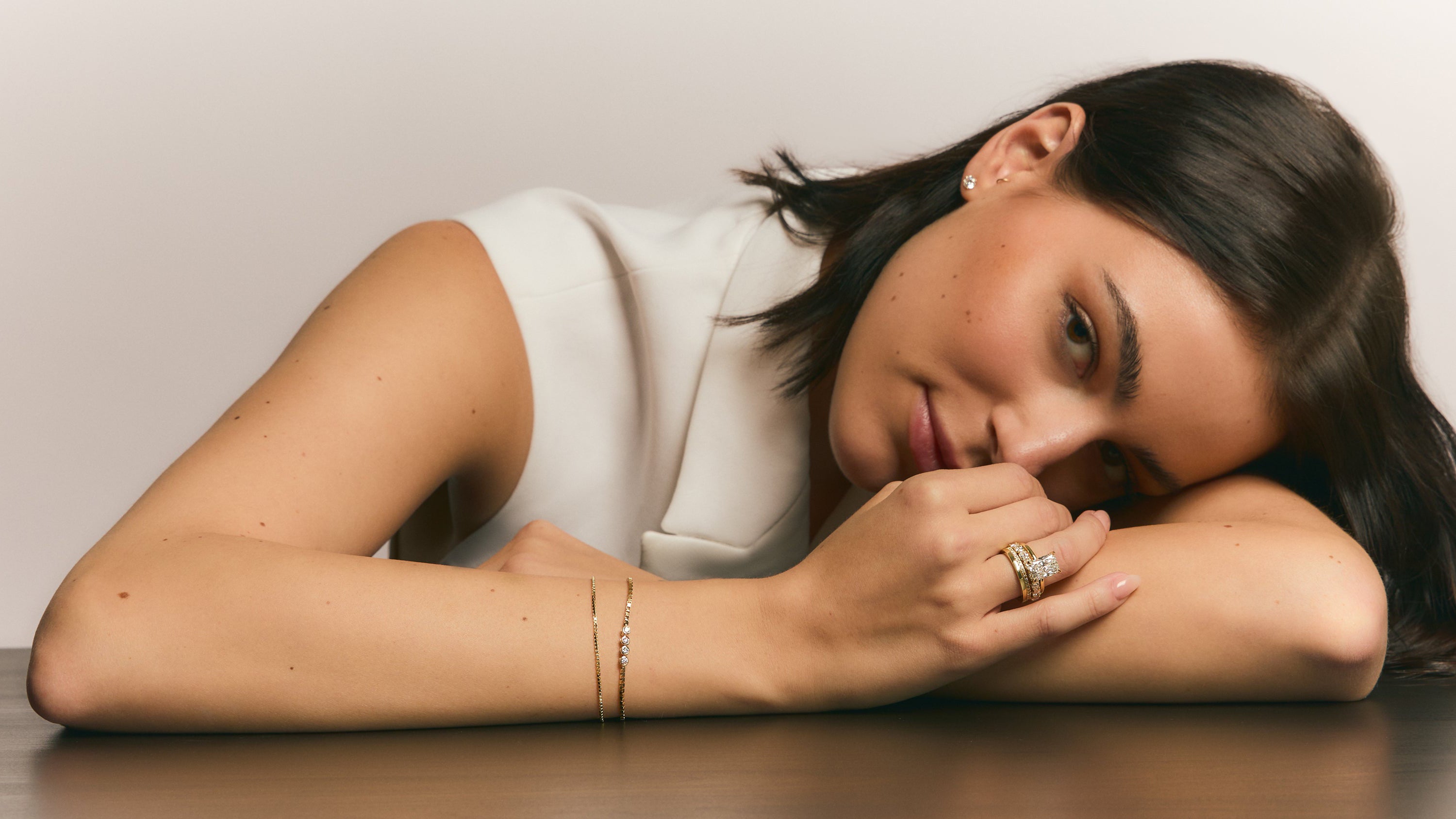 woman smiling with gold jewelry and diamond engagement ring